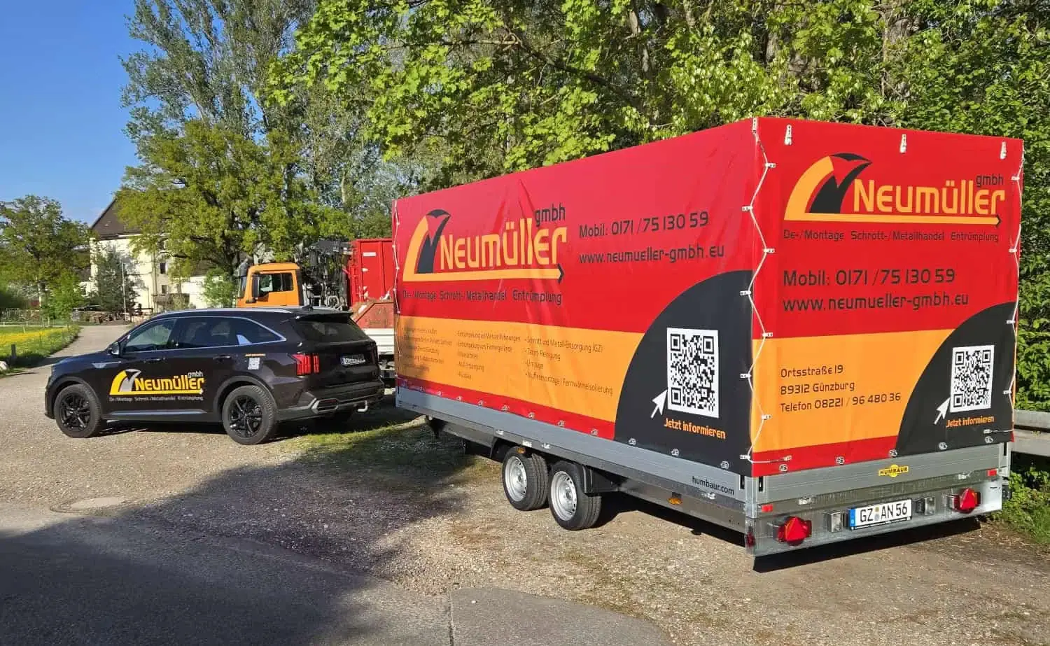 Beschrifteter Anhänger und Firmenfahrzeug der Neumüller GmbH auf dem Betriebsgelände